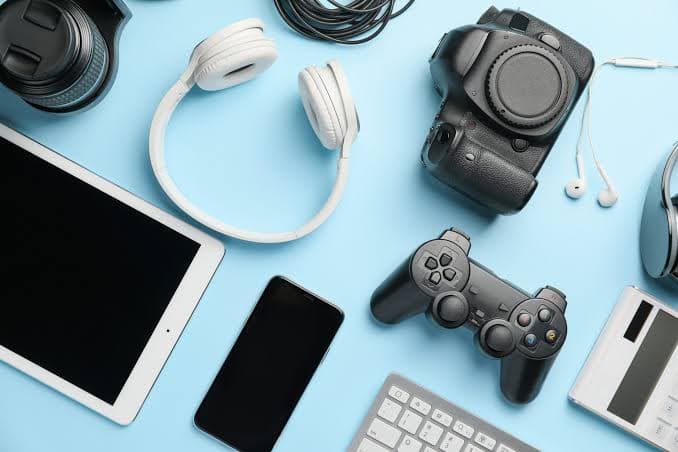 Consumer electronics and personal devices arranged on a blue surface